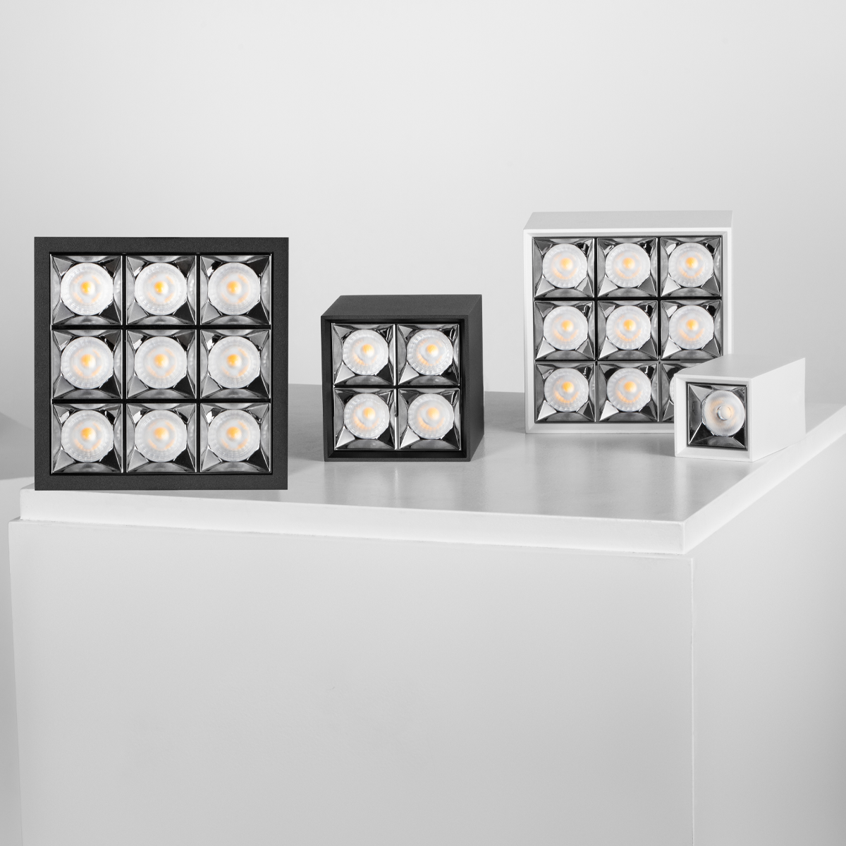 Three square light fixtures with multiple small lights on a white surface