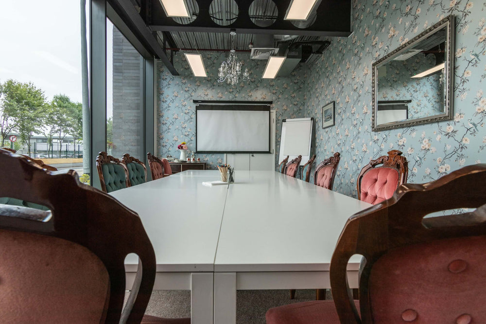 Conference room with floral wallpaper, a large white table, and red chairs. With LED Panels