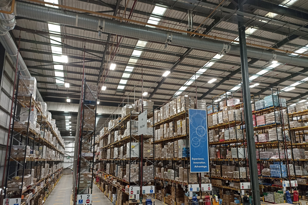 Large warehouse with high shelves filled with boxes and pallets.