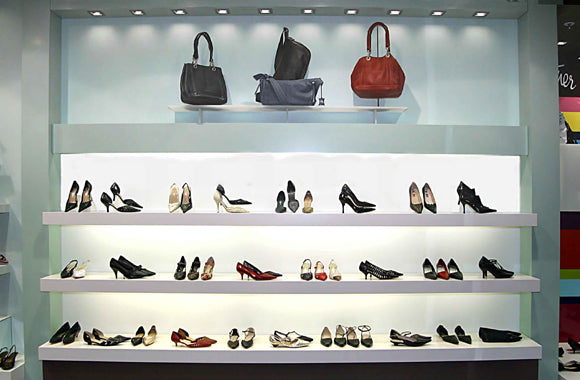 Shelves displaying a variety of shoes and handbags in a store setting.