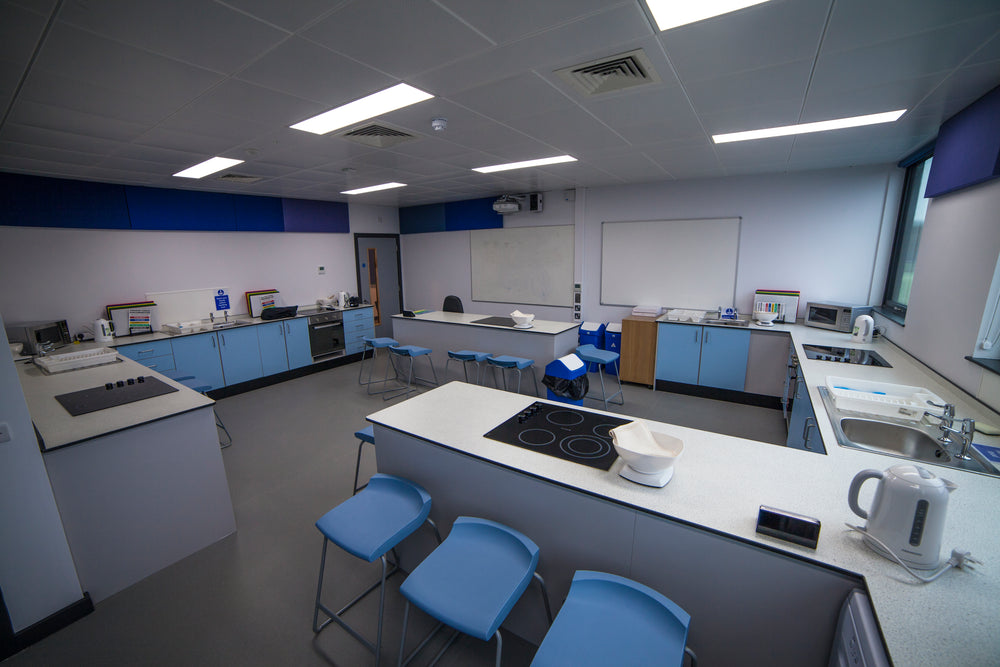 Modern kitchen or laboratory with white countertops, blue cabinets, and various appliances.