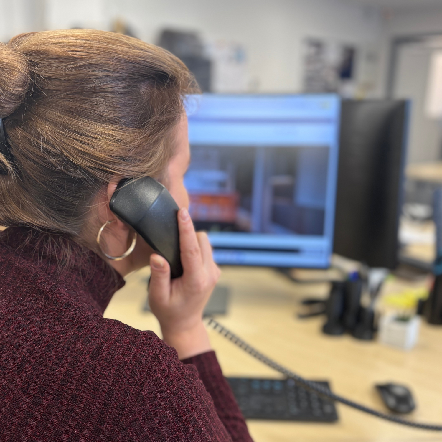 Person on the phone at a desk with a computer in the background