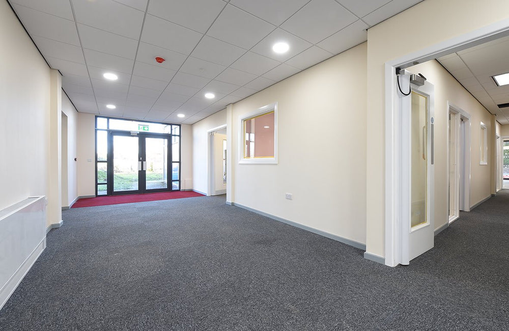 Empty office hallway with carpeted floor and large windows
