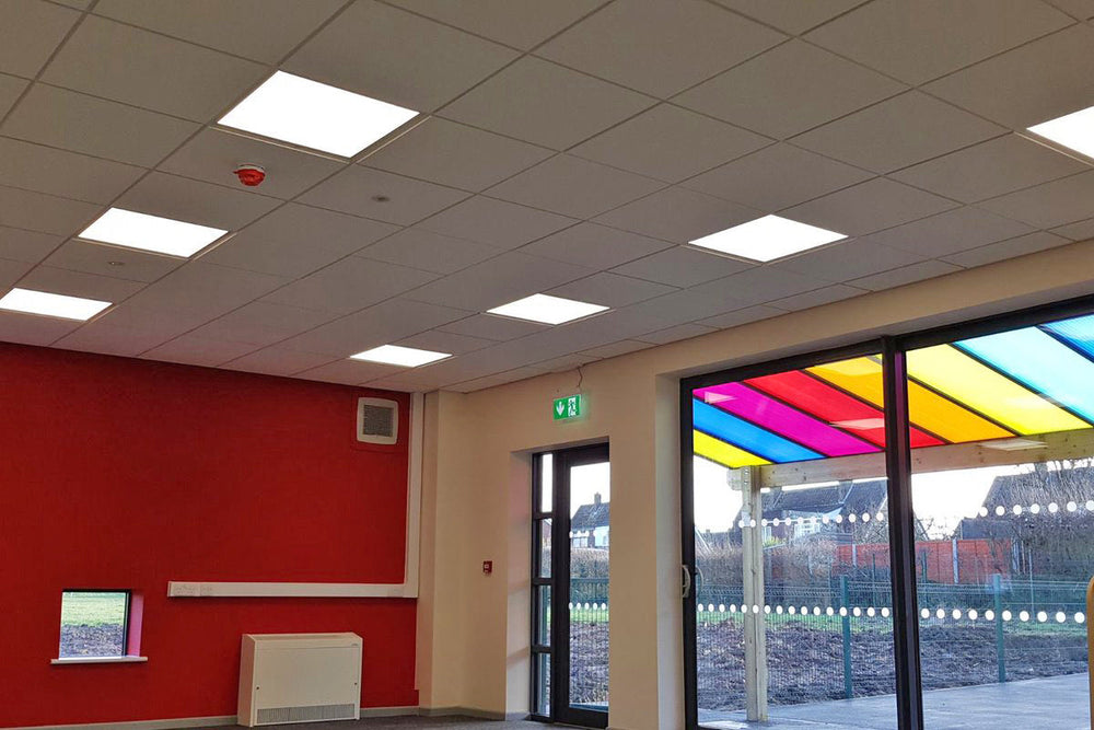 Modern office interior with red wall, ceiling  LED lights, and a colorful glass door.