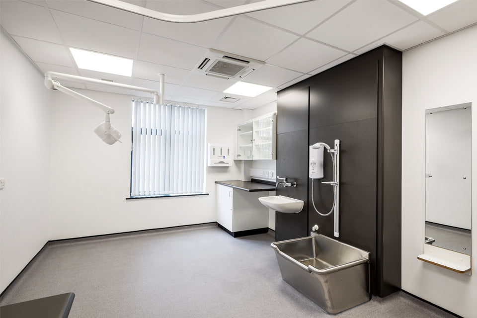 Modern medical examination room with sink, cabinets, and medical equipment.